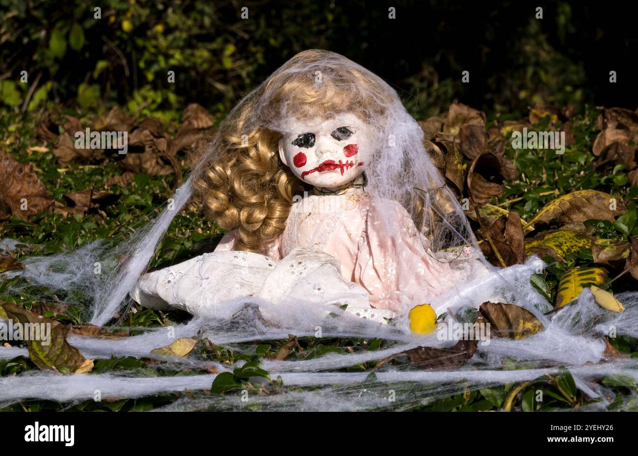 Scary Halloween doll with red mouth in hedgerow Stock Photo