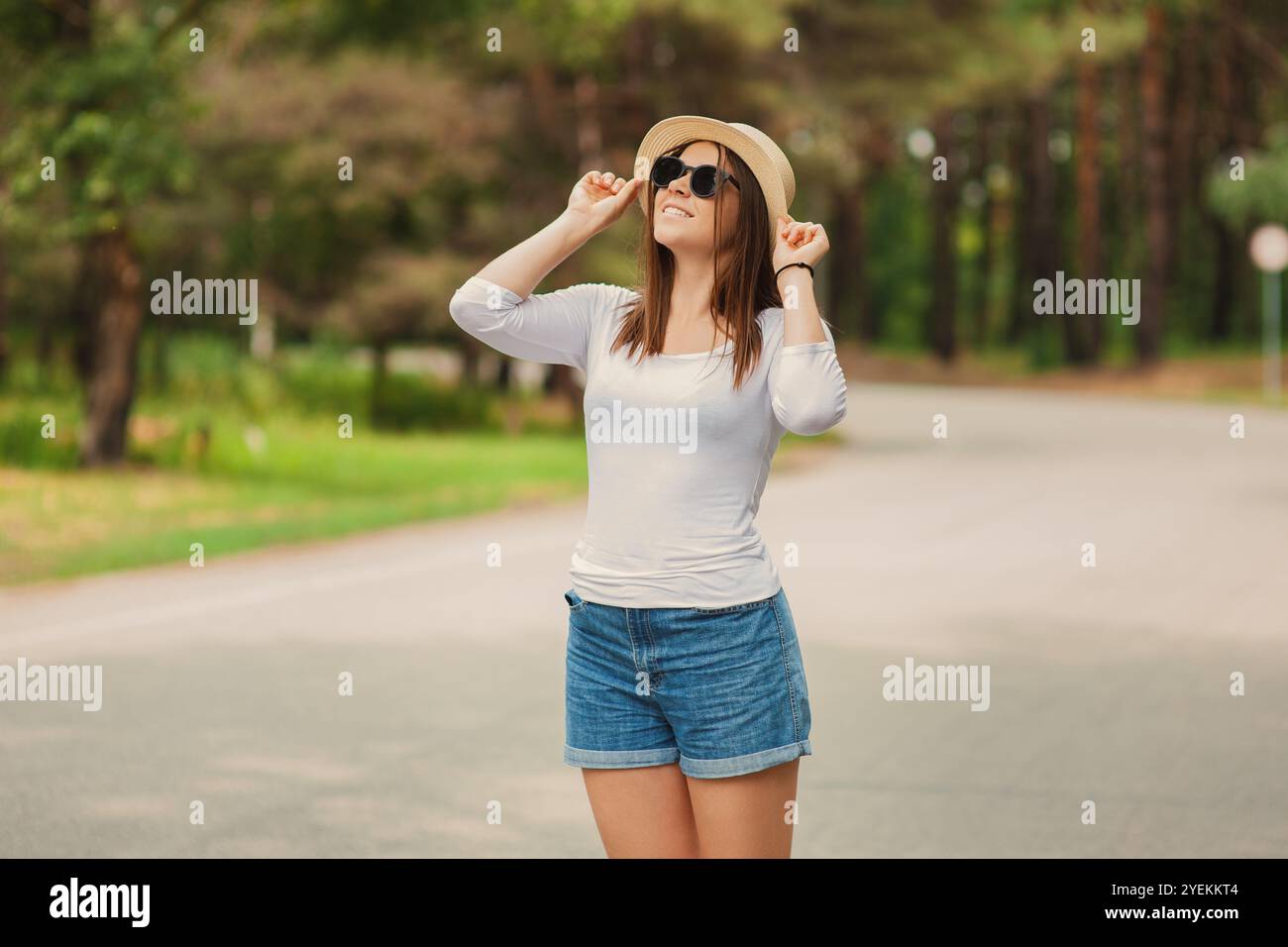 A cute young woman wearing a sun hat in sunglasses standing outdoors in ...