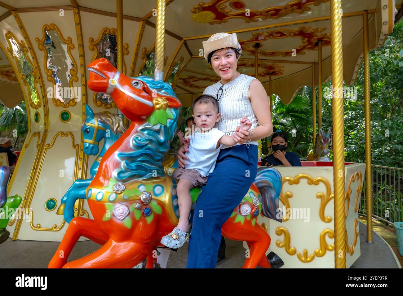 Ho Chi Minh City Zoo, Viet Nam - October 26, 2024: Portrait of a happy mother and child on a carousel horse at Ho Chi Minh City Zoo, Viet Nam. Stock Photo