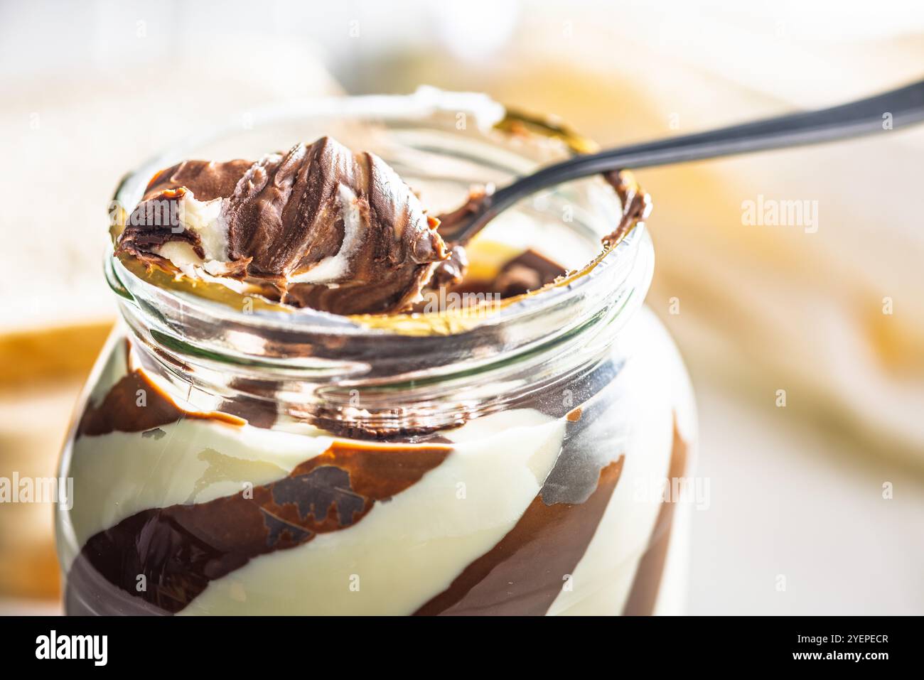 Chocolate cream spread on spoon in a jar. Stock Photo
