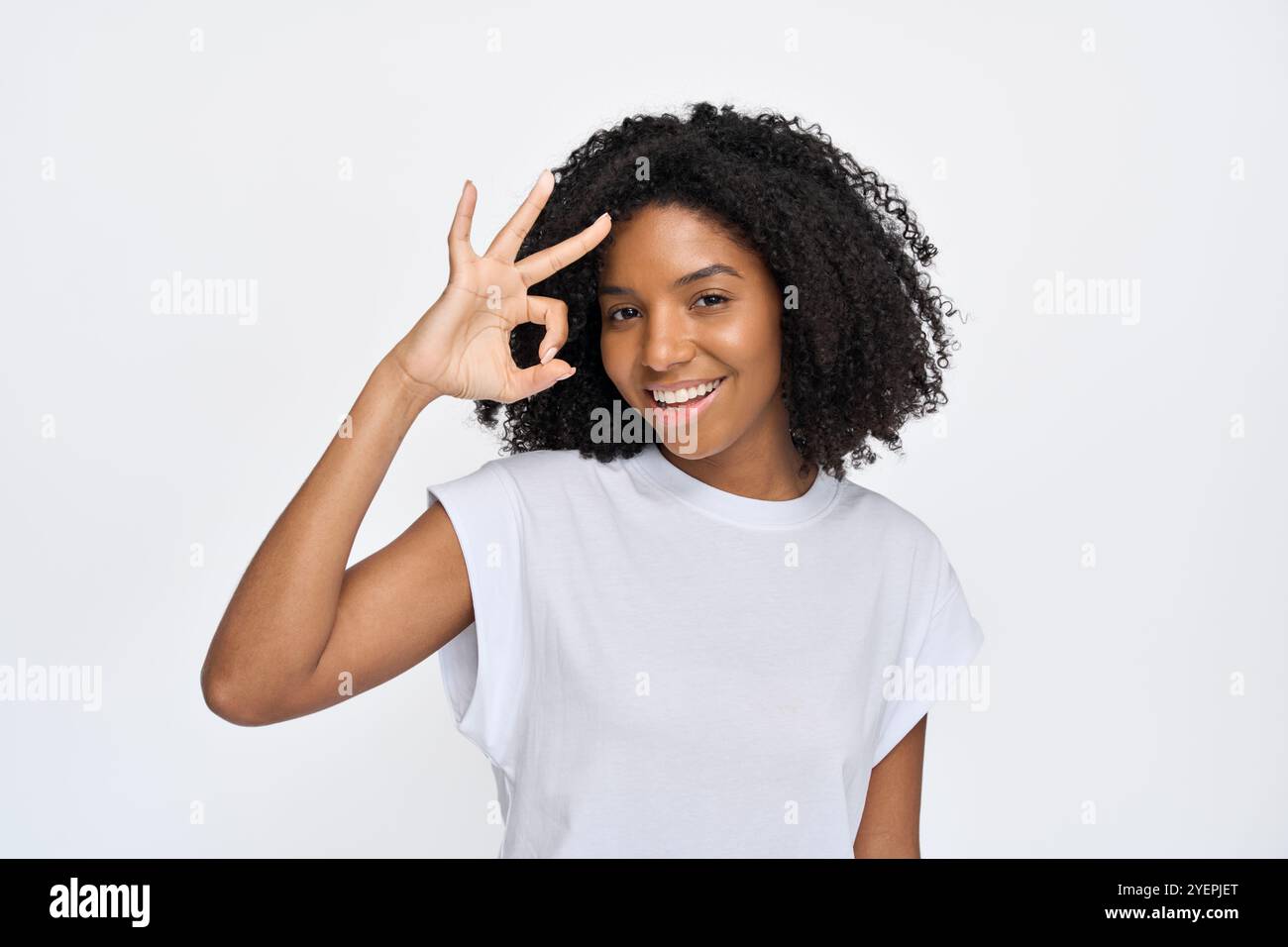 Happy young African woman showing ok sign isolated at white wall ...