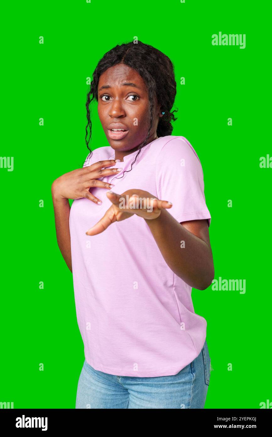 Surprised young woman against a vibrant green background expressing astonishment or shock Stock Photo