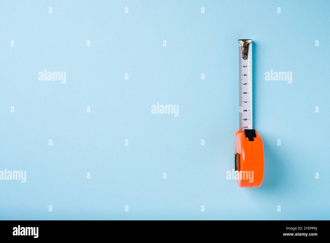 Orange retractable tape measure on blue background Stock Photo