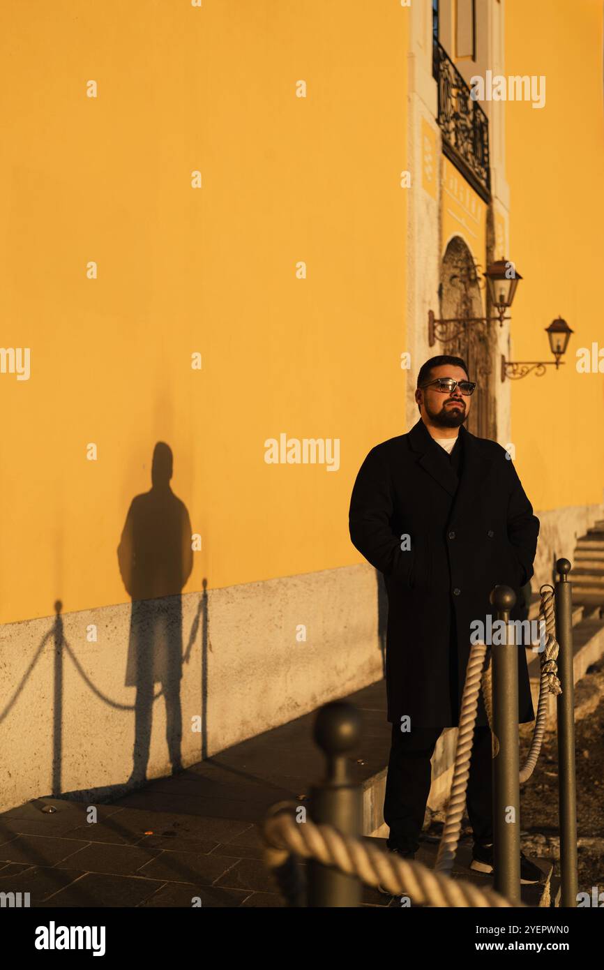 Portrait of a young adult handsome man and his shadow on yellow wall Stock Photo