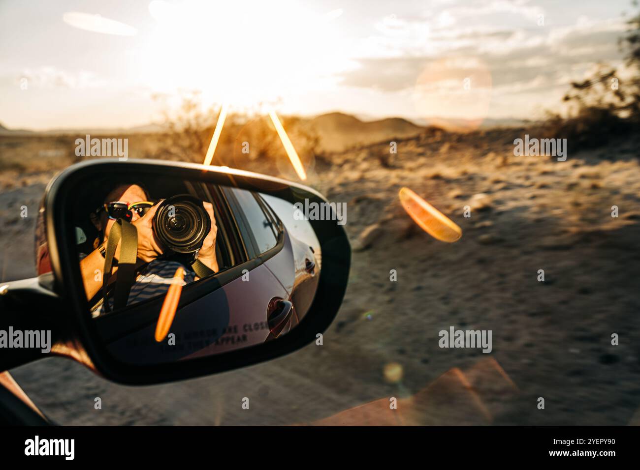 Photographer in a car mirror capturing a desert sunset scene Stock ...