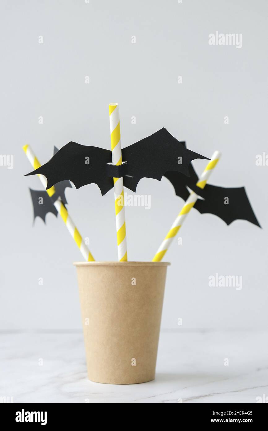 Black paper bat on drinking straw. Halloween party decoration. DIY