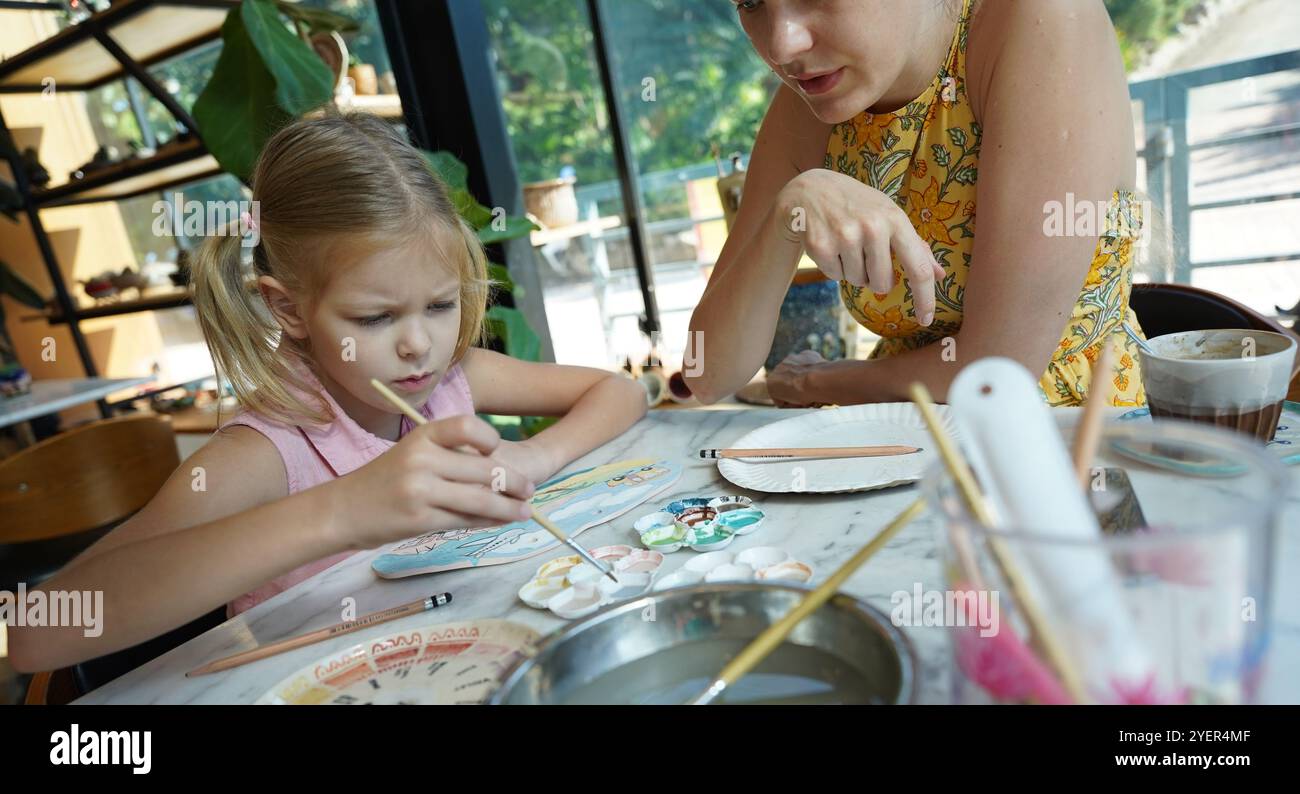 A young mother and her daughter enjoy a creative art session at home ...
