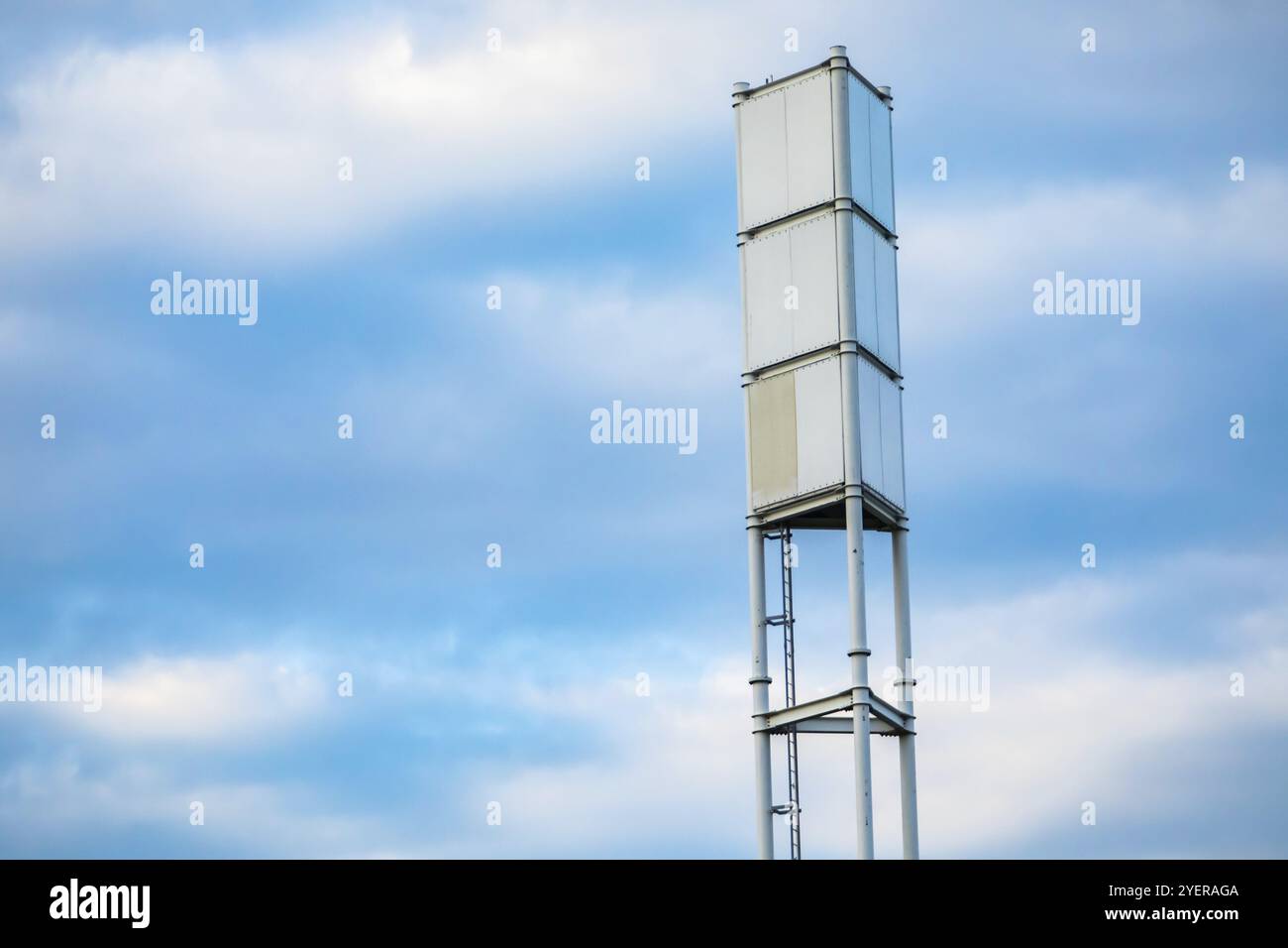 A low angle view of a radio signal tower, tall steel frame with access ladder. Signal broadcasting infrastructure against a blue sky with copy space Stock Photo