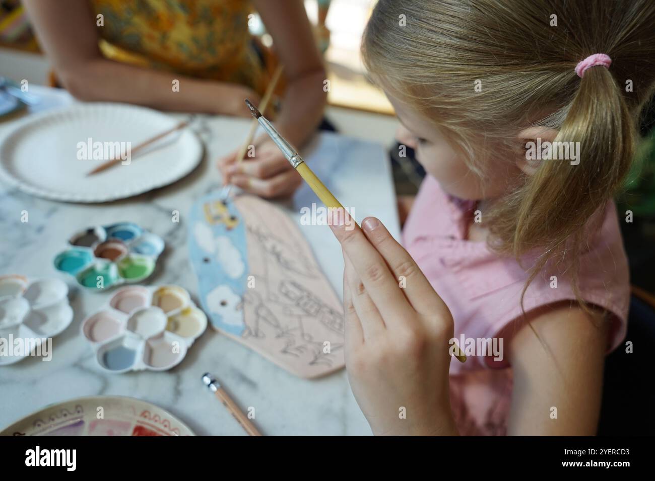 A young mother and her daughter enjoy a creative art session at home ...