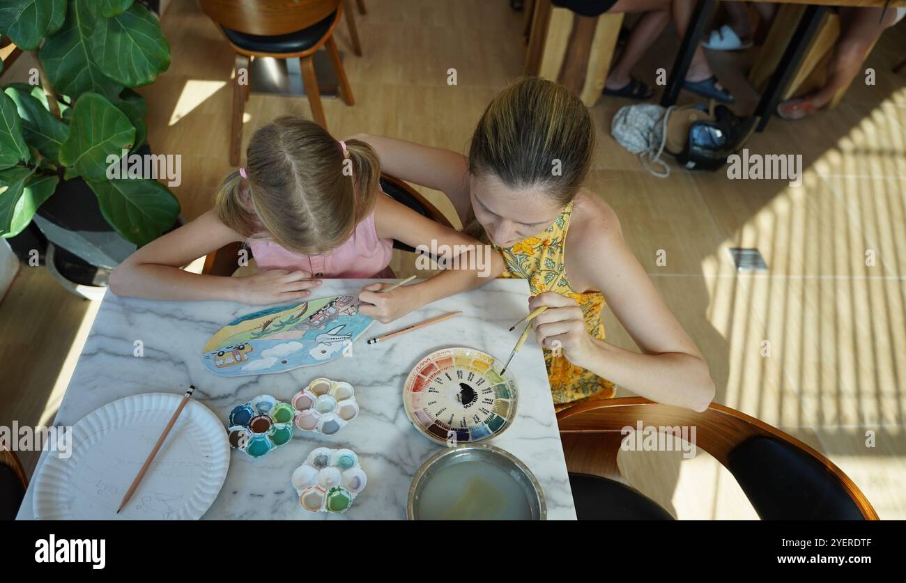 A young mother and her daughter enjoy a creative art session at home ...