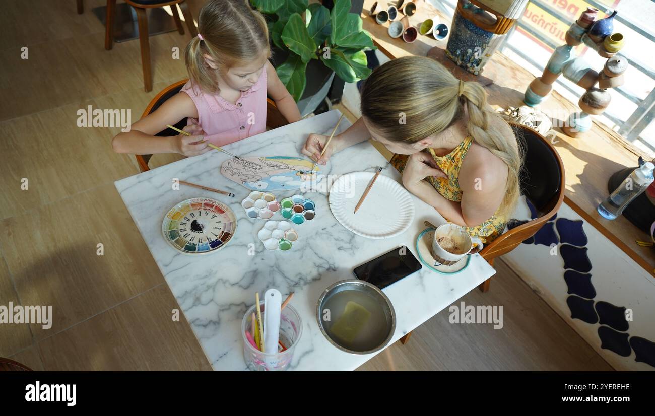 A young mother and her daughter enjoy a creative art session at home ...