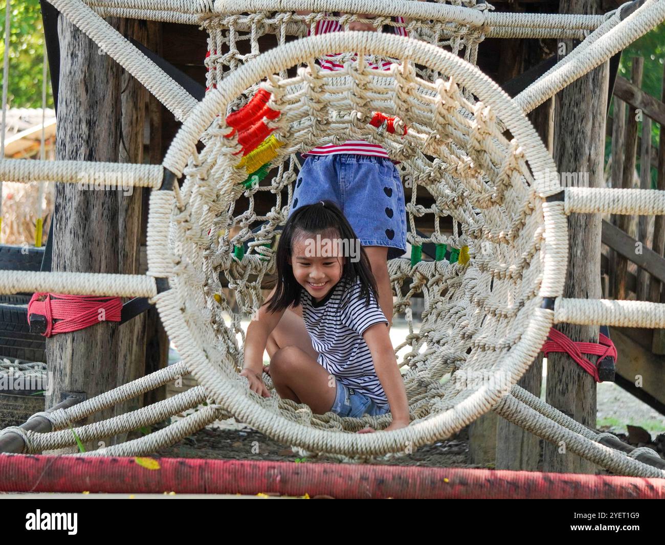 Children play outdoors on a wooden playground in a park. Happy girl ...