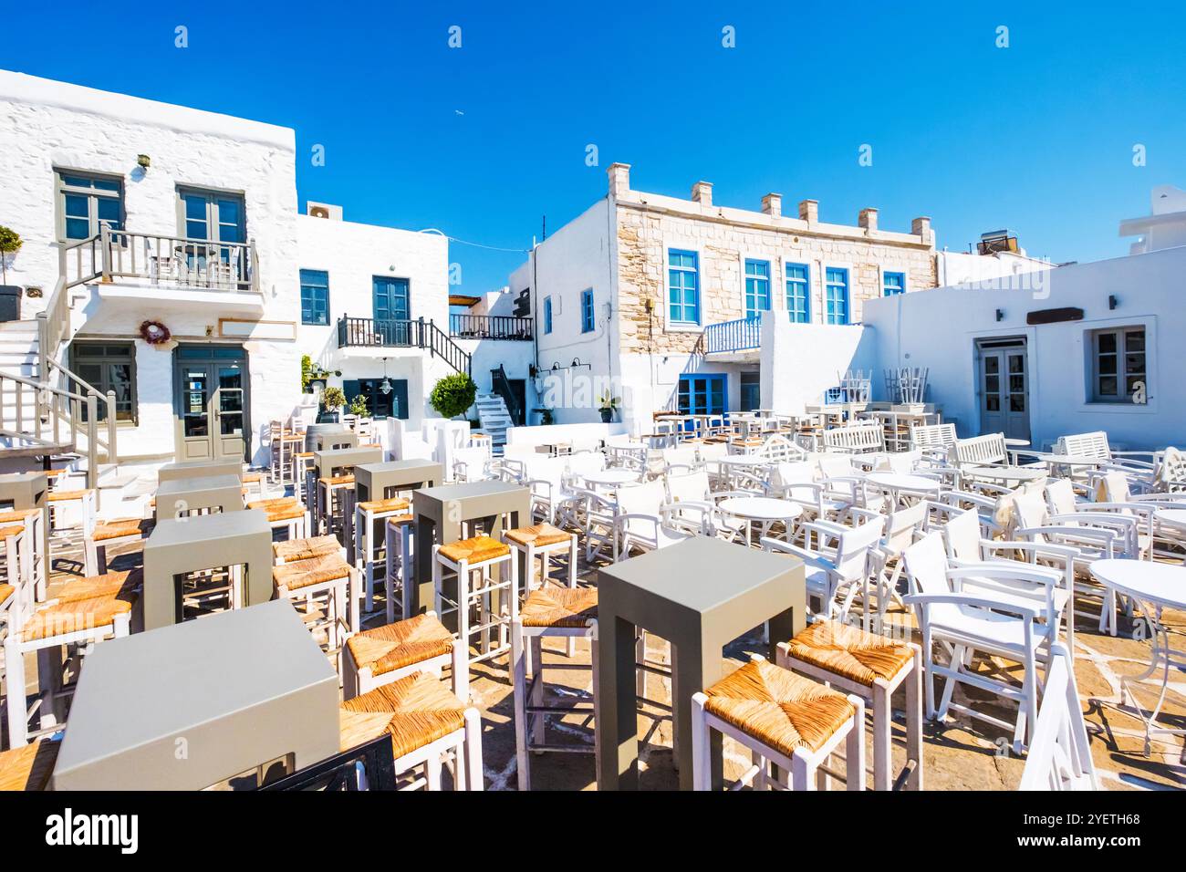 Tables and chairs outdoors in traditional Greek cafe. Typical Greek taverna in Naoussa port, Paros island, Greece Stock Photo