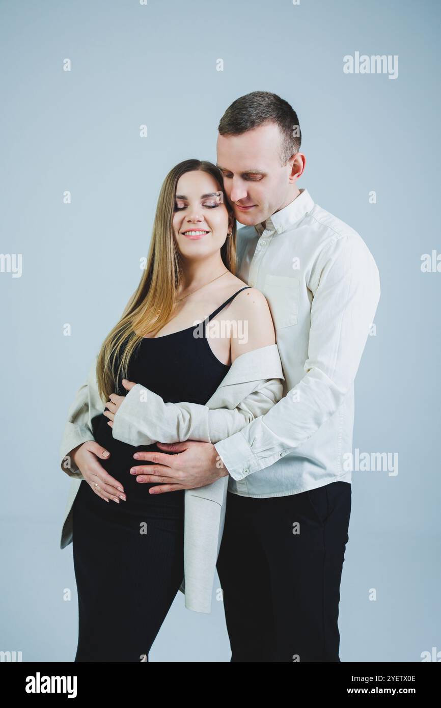 Happy young man standing with his pregnant wife and hugging her belly ...