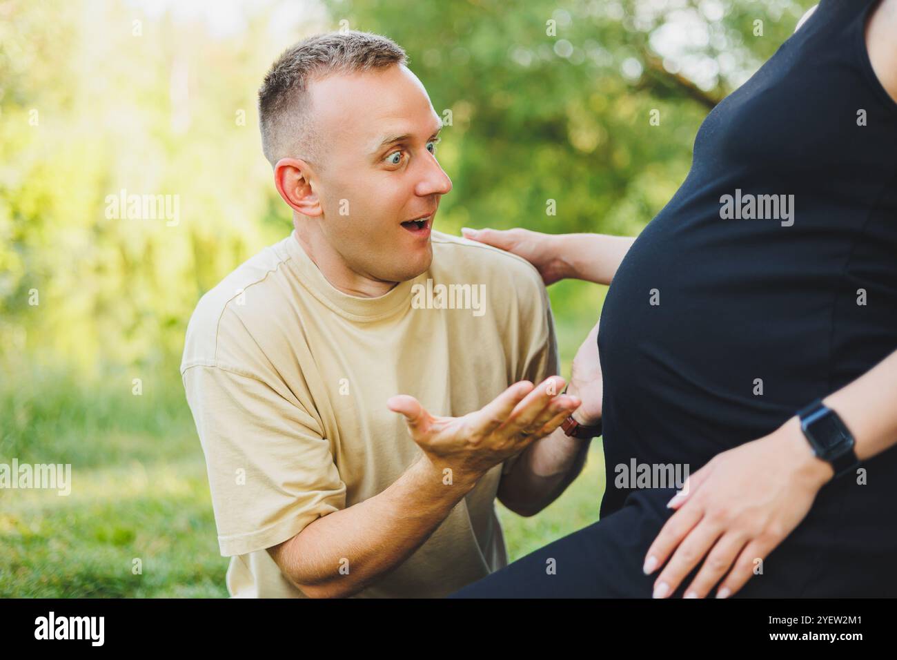 A man hugs the belly of his pregnant wife. Pregnancy. A happy couple is ...