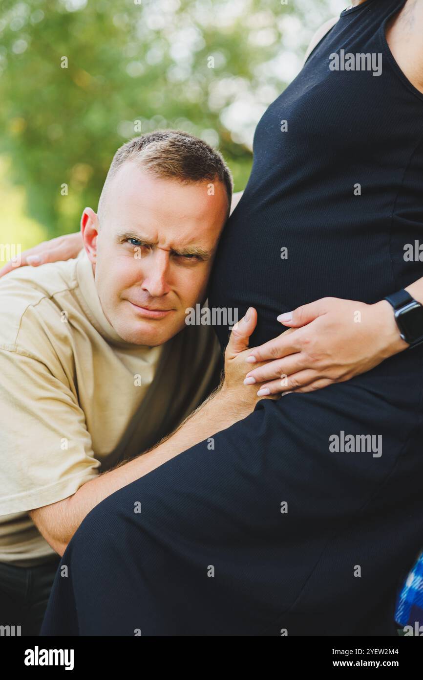 A man hugs the belly of his pregnant wife. Pregnancy. A happy couple is ...