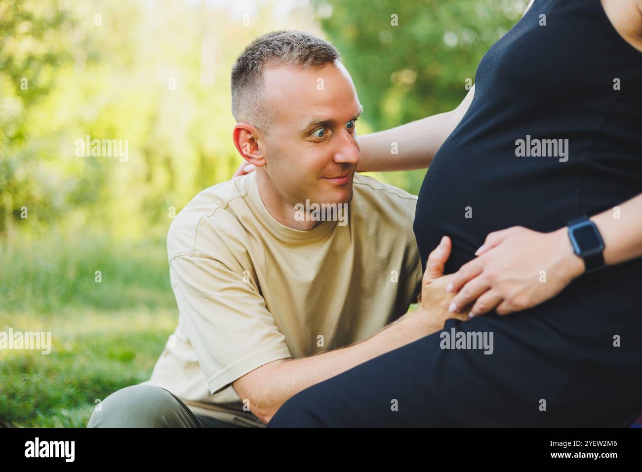 A man hugs the belly of his pregnant wife. Pregnancy. A happy couple is ...