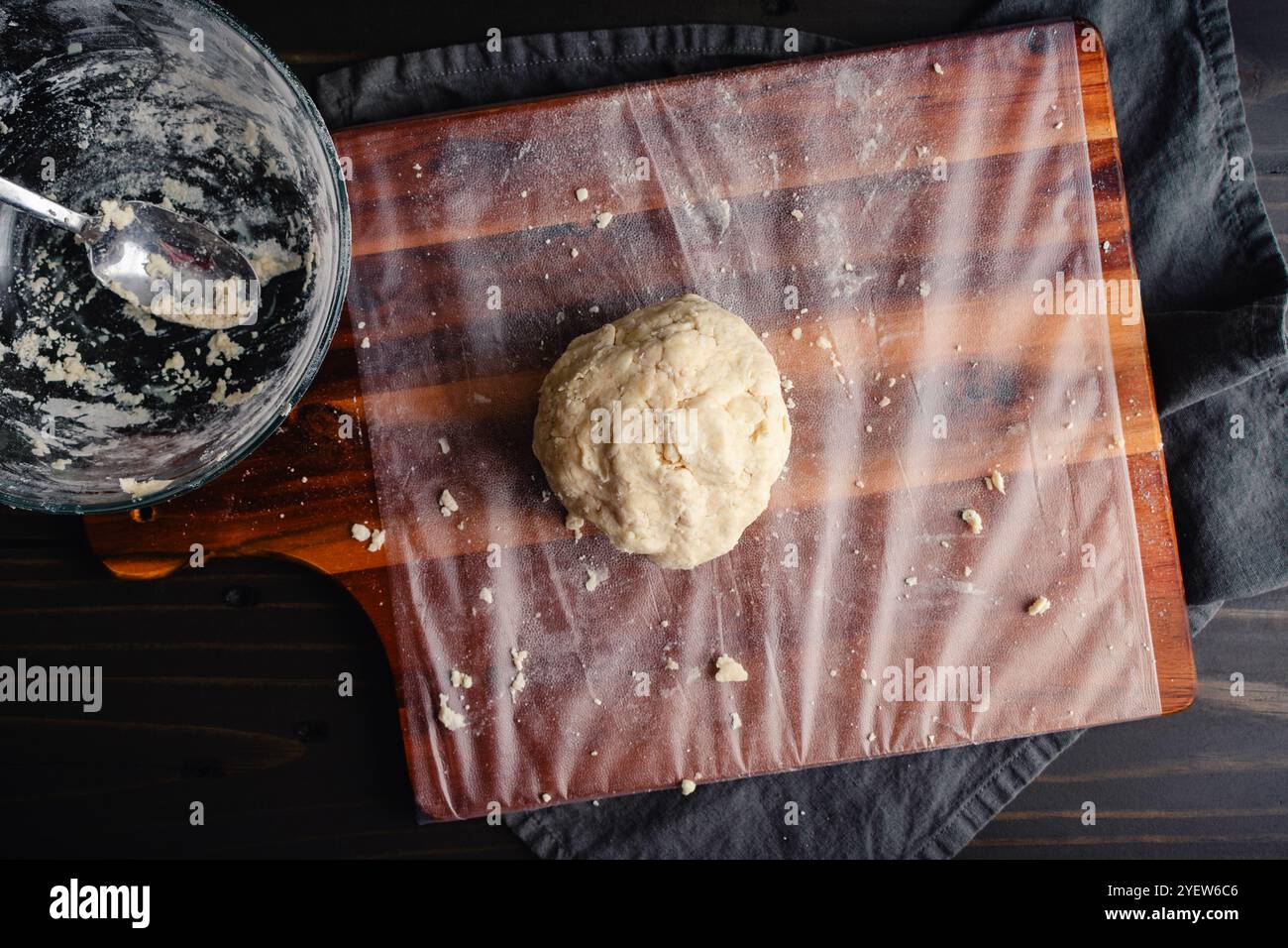 Ball of Homemade Pie Crust Dough on a Cutting Board: Freshly made pie crust dough on a messy plastic-wrapped wooden chopping board Stock Photo