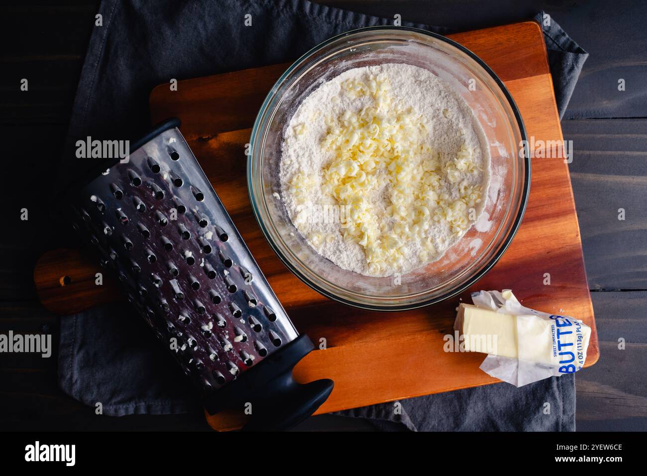 Making Pie Crust Dough with Frozen Grated Butter: Frozen butter shredded into dry ingredients for homemade pie crust dough Stock Photo