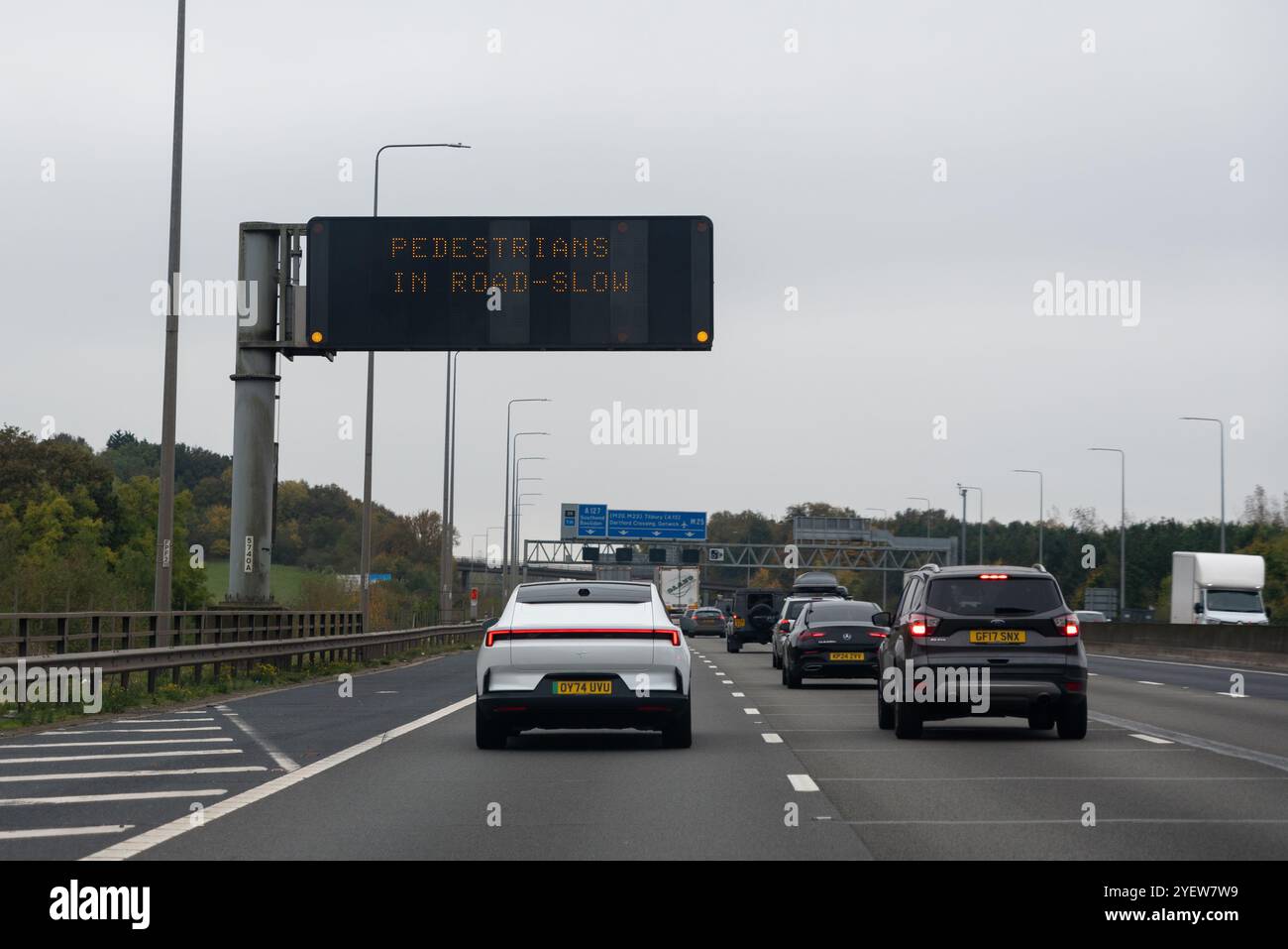 Pedestrians in road, slow, warning sign on the M25 near Brentwood, Essex, UK Stock Photo