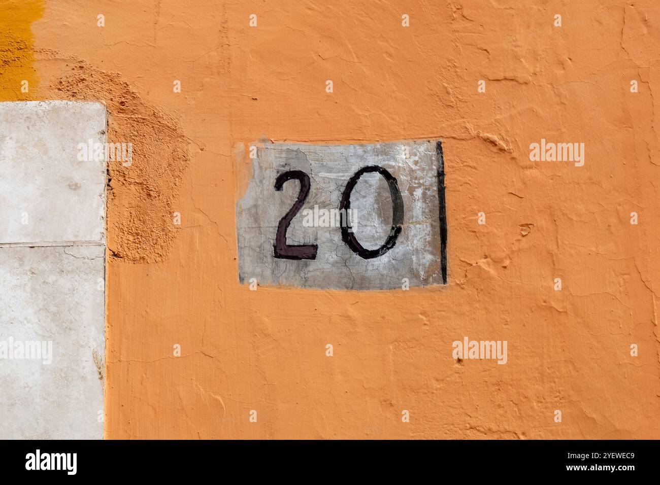 Number twenty on rough panel on plaster wall Stock Photo
