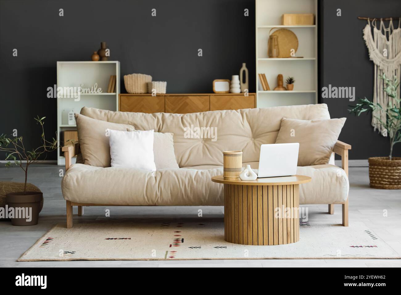 Comfortable sofa and coffee table with laptop in interior of living ...