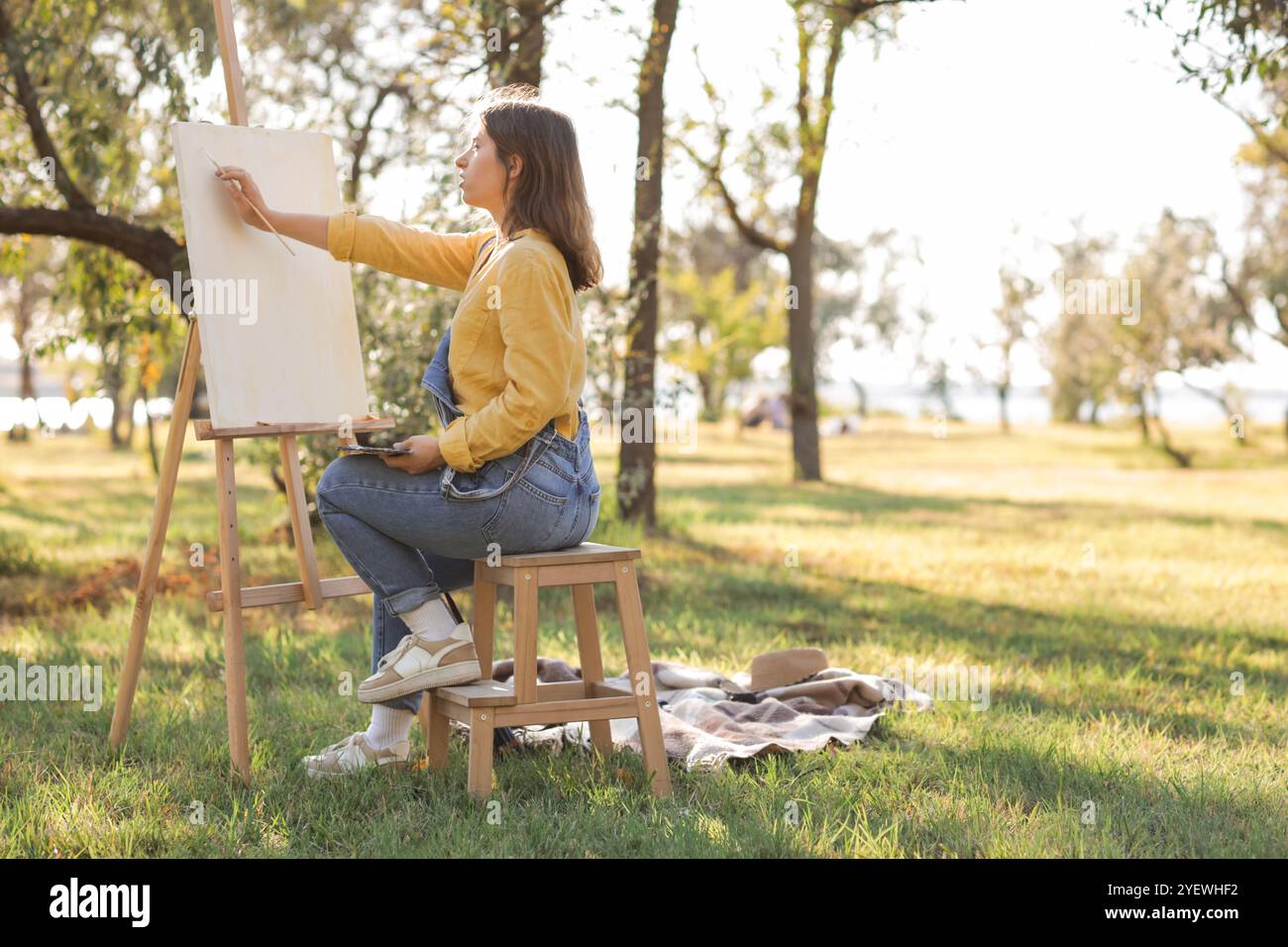 Female artist with palette painting on canvas in park Stock Photo - Alamy