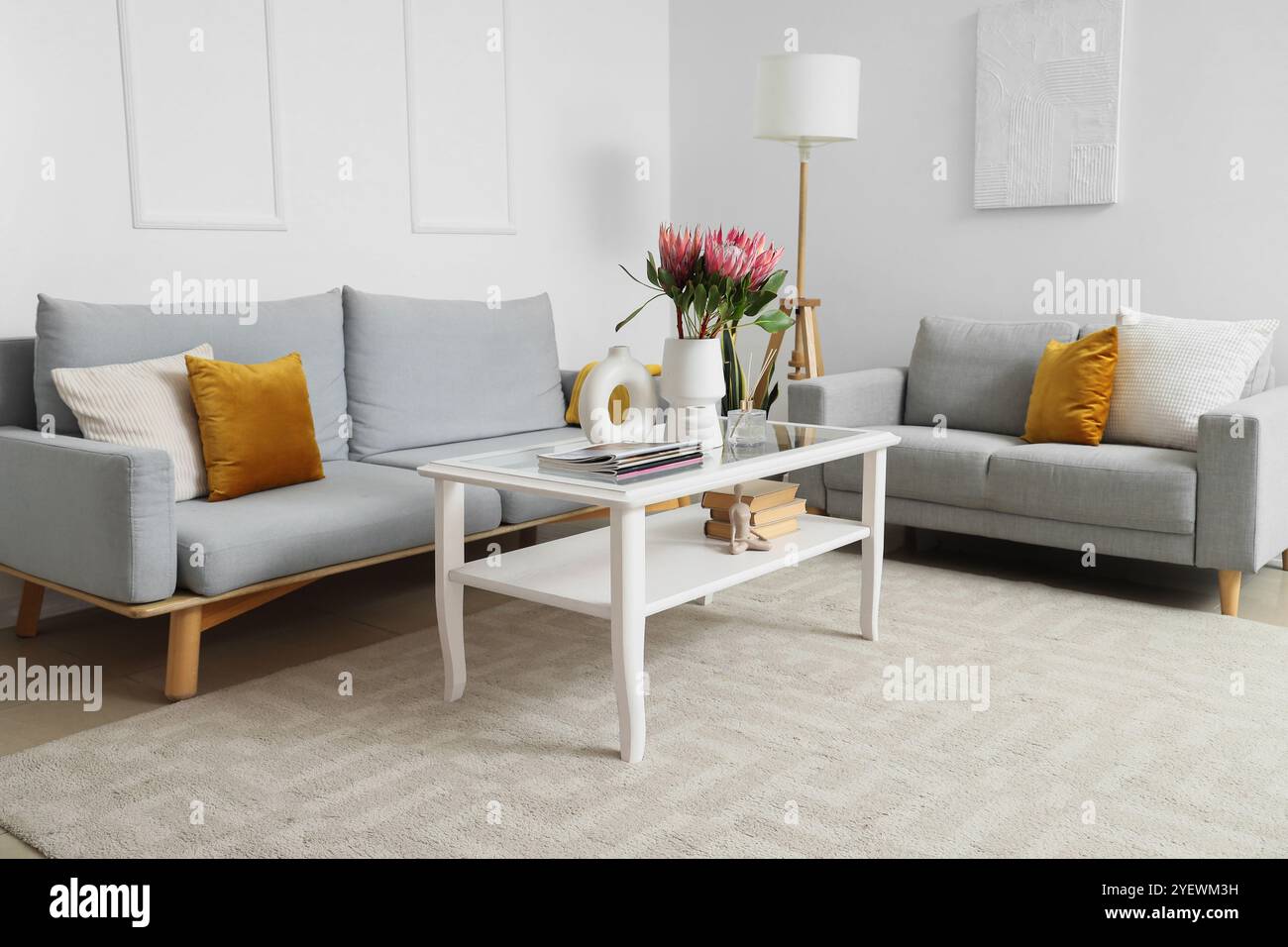 Sofas and protea flowers in vase on glass coffee table in living room ...