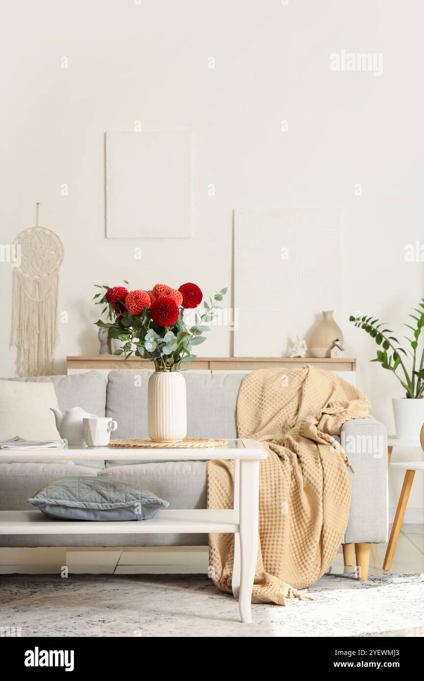 Cozy sofa and dahlia flowers in vase on glass coffee table in living ...