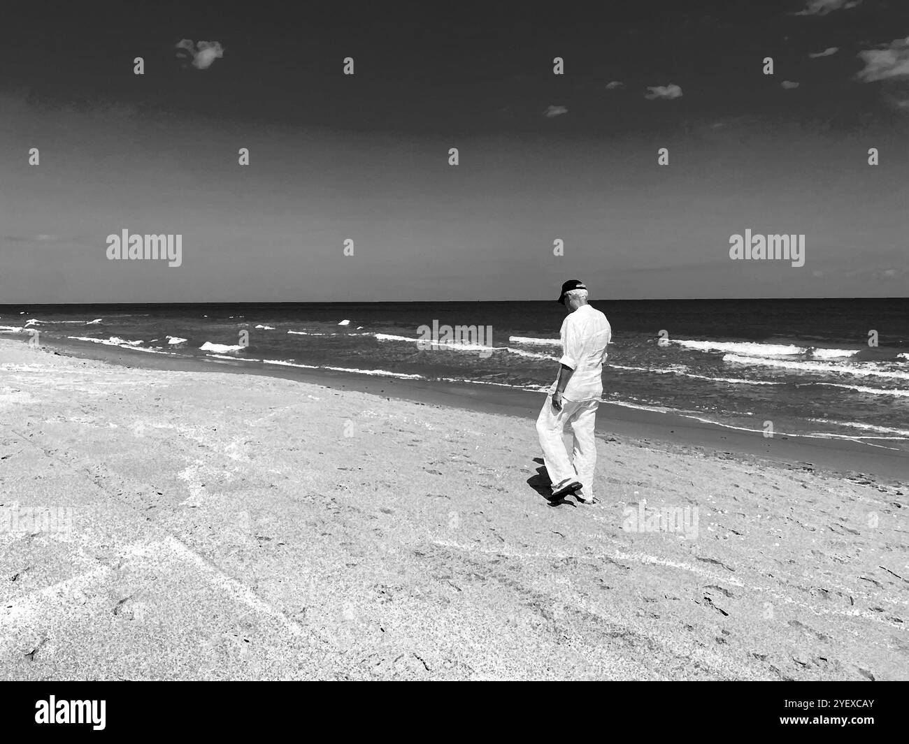 Healthy senior man walking on the beach along the ocean waves. - Smartphone Captured Stock Image