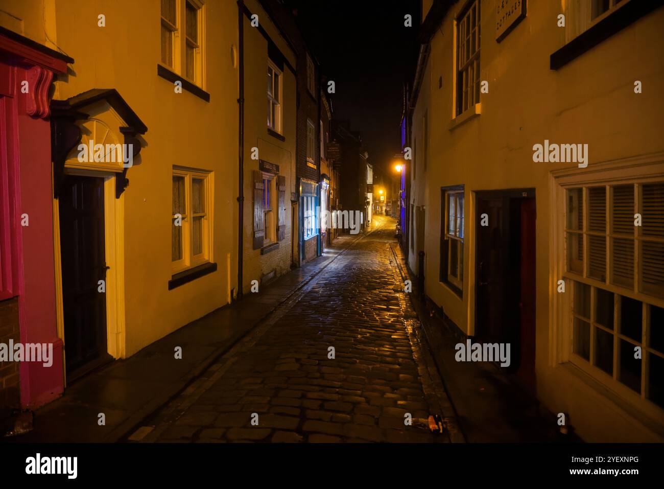 Painted buildings in the gloom of a dimly lit street at night in Whitby ...
