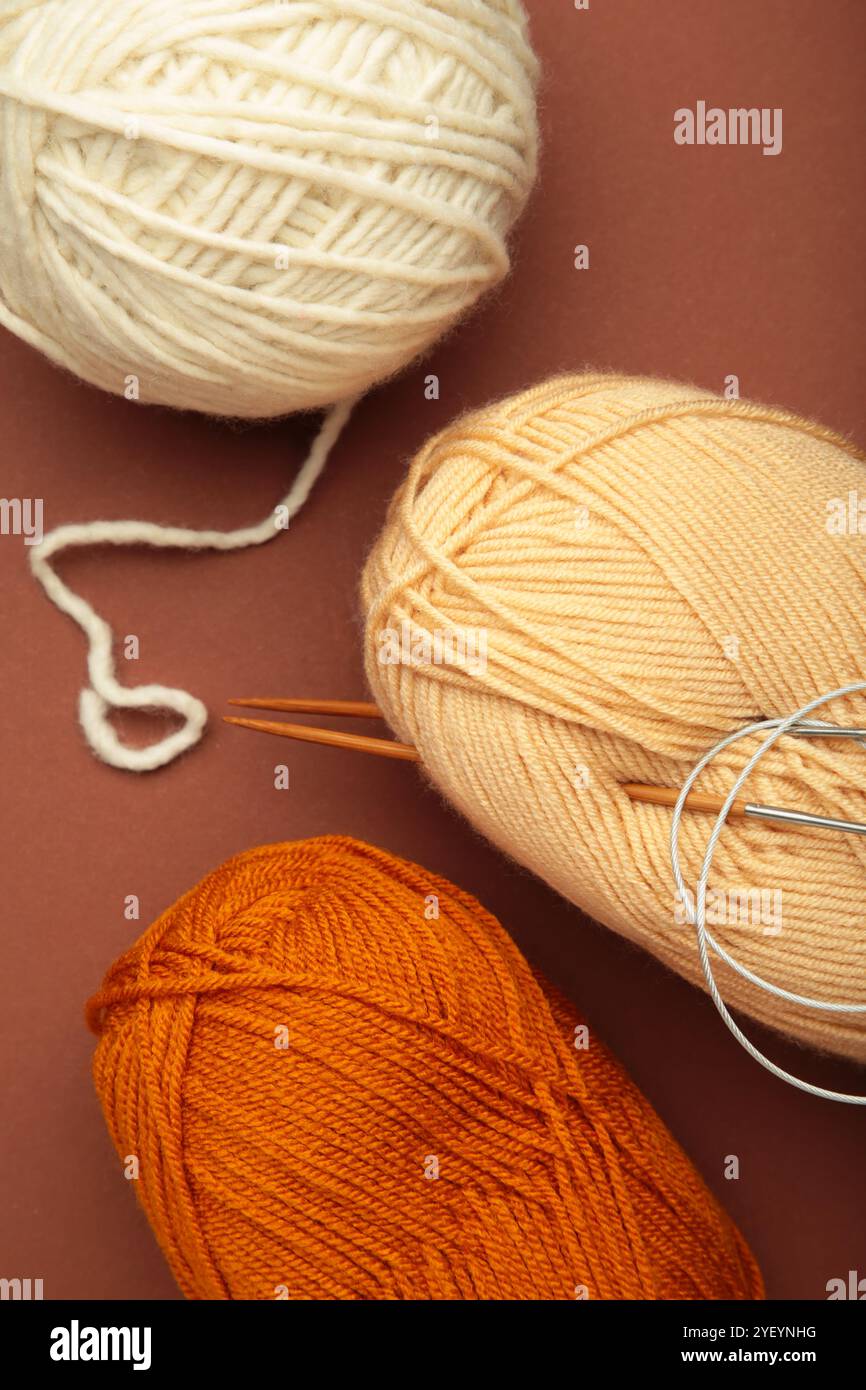 Different yarns, knitting needles on brown background. Top view Stock Photo
