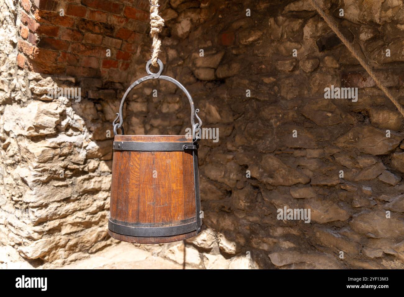 Old stone well with wooden bucket in front of a stone wall Stock Photo