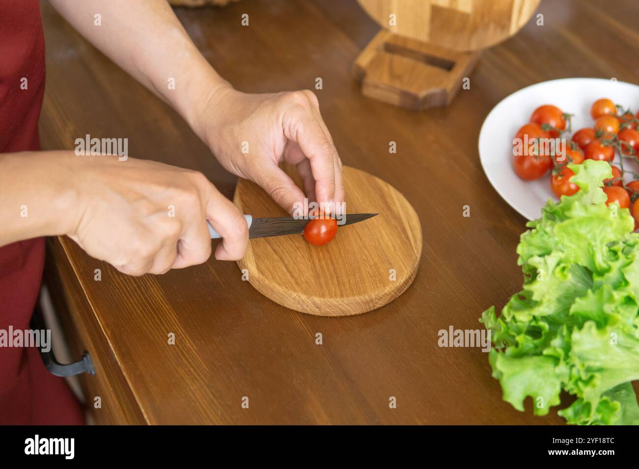 person cutting cherry tomatoes on cutting board Stock Photo