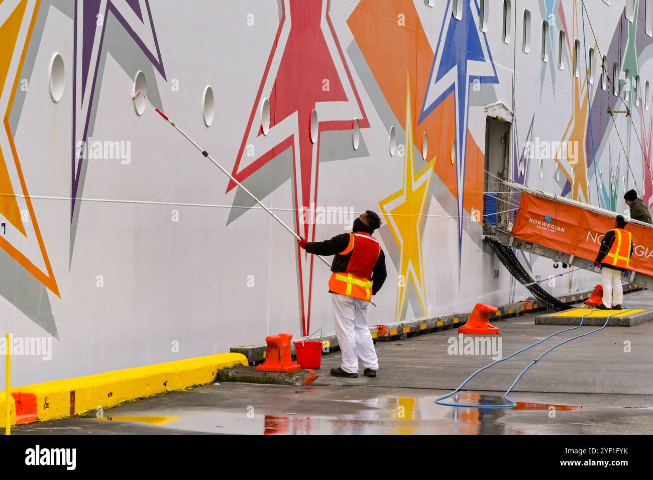 Akureyri, Iceland - 24 August 2024: Crew member using a long pole and roller to paint the side of the Norwegian Star cruise ship Stock Photo