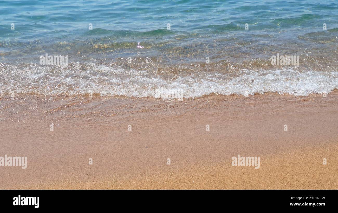 Sea background. Clear transparent water, waves inn sunny day with much sand and stones. Stock Photo