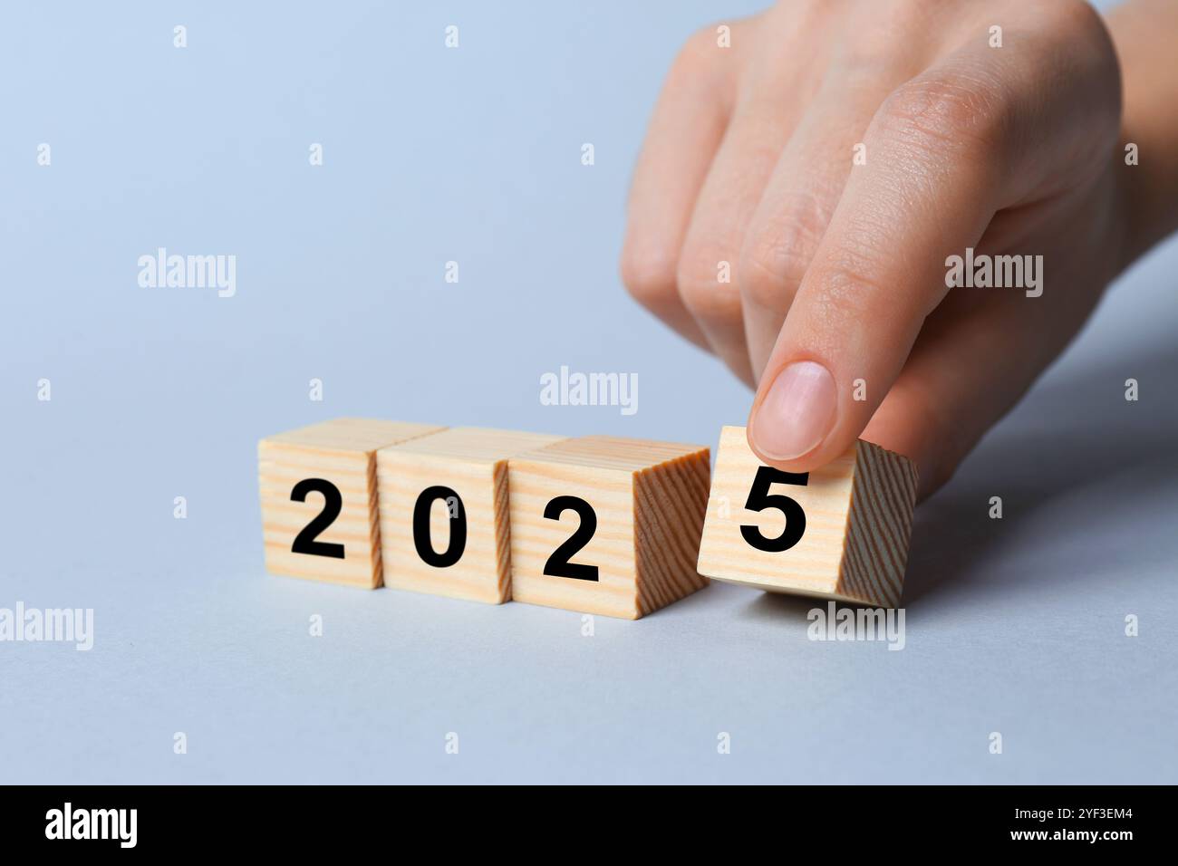 2025 New Year. Woman putting wooden cube with number 5 on light grey background, closeup Stock Photo