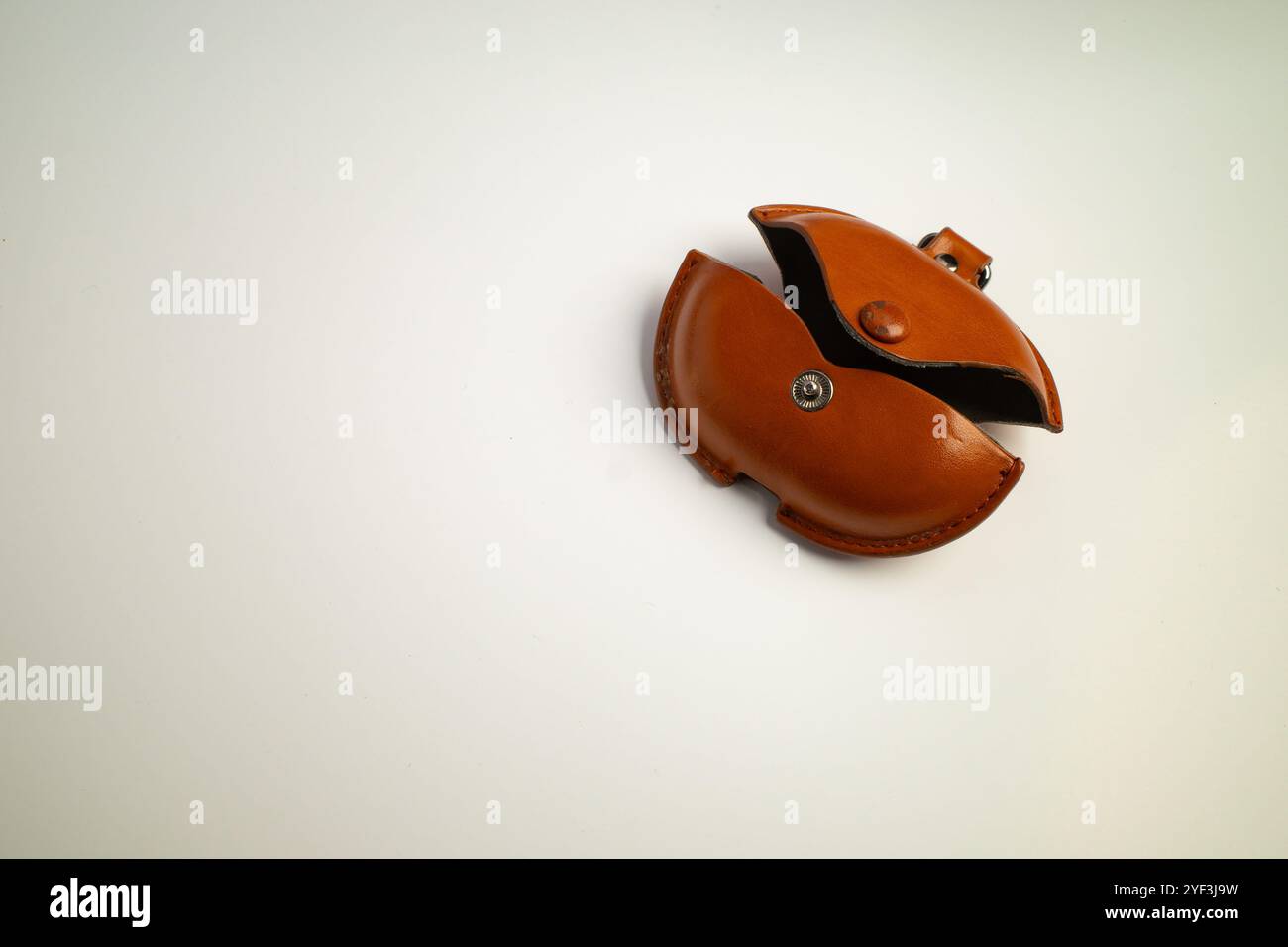 Small brown leather coin pouch with snap closure placed on a surface Stock Photo