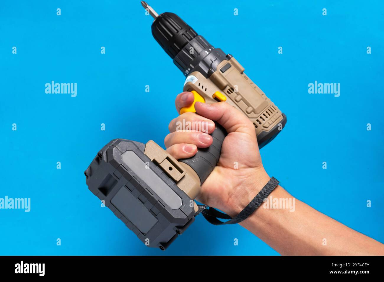 Man hand holds cordless screwdriver on blue background Stock Photo