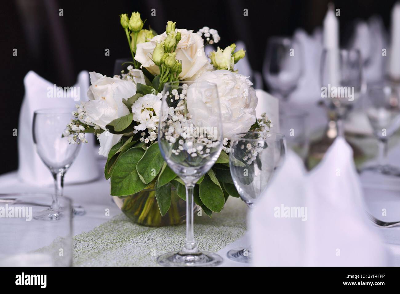 Beautiful white flower bouquets with drinking glasses at Wedding table setting Stock Photo