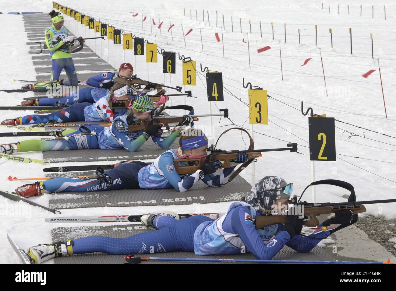 Group sportswoman biathlete aiming, rifle shooting and reloading rifle in prone position. Biathletes shooting range during Junior biathlon competition Stock Photo