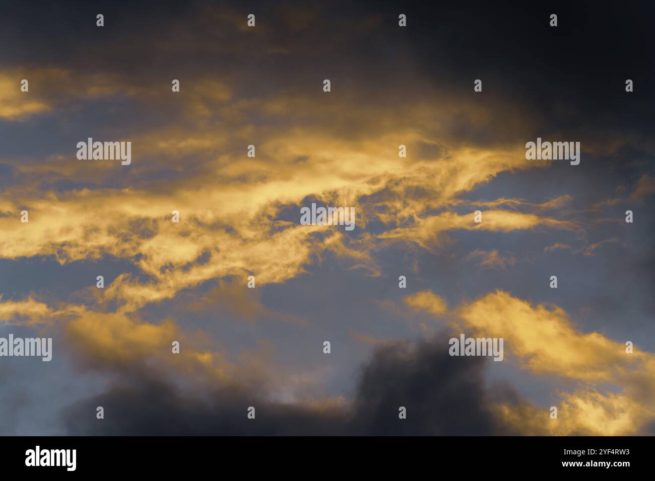 Stunning fluffy thunderstorm clouds illuminated by disappearing rays at sunset and dark thunderclouds floating across sunny blue sky to change season Stock Photo