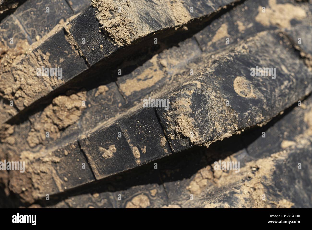 Close-up of old used rubber mud terrain tire with worn wear-resistant tread. Black muddy off-road tire on four-wheel drive truck with adhering dirt af Stock Photo