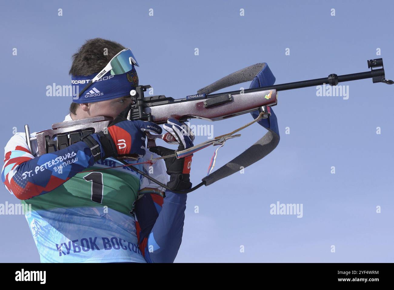 Sportsman biathlete aiming, rifle shooting in standing position. Junior biathlon competitions East Cup. Saint Petersburg biathlete Amirbekov Artem in Stock Photo