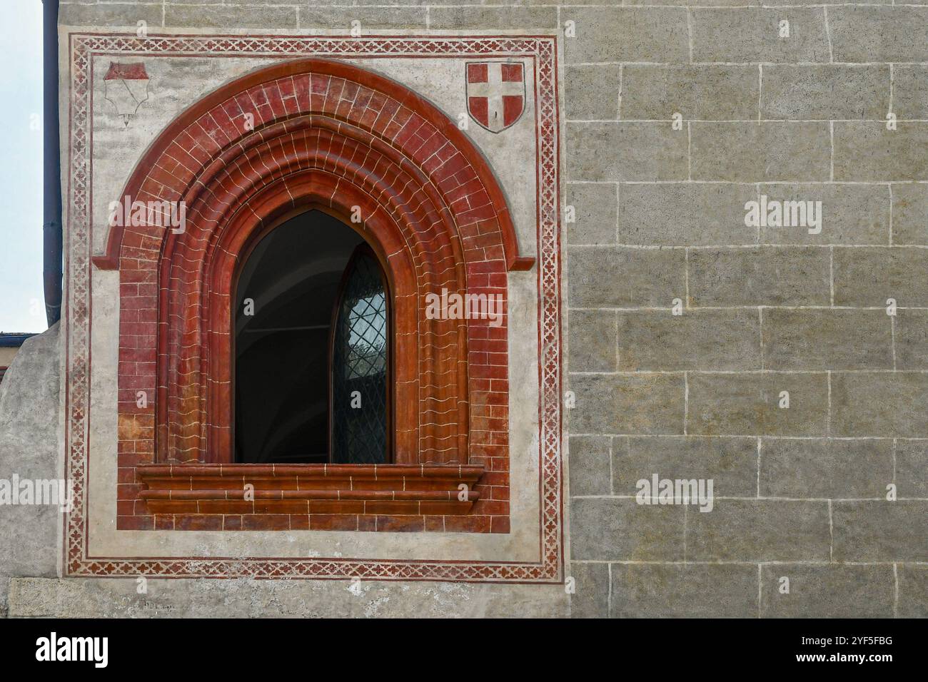 A pointed window with red brick frame and frescoed coat of arms on the ...