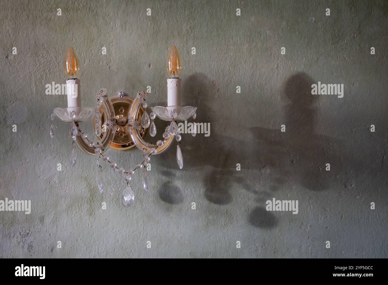 Close-up of wall lamp of classic style  on a plaster wall. Textured decorative light green plaster wall with vintage wall lamp. Background. Stock Photo