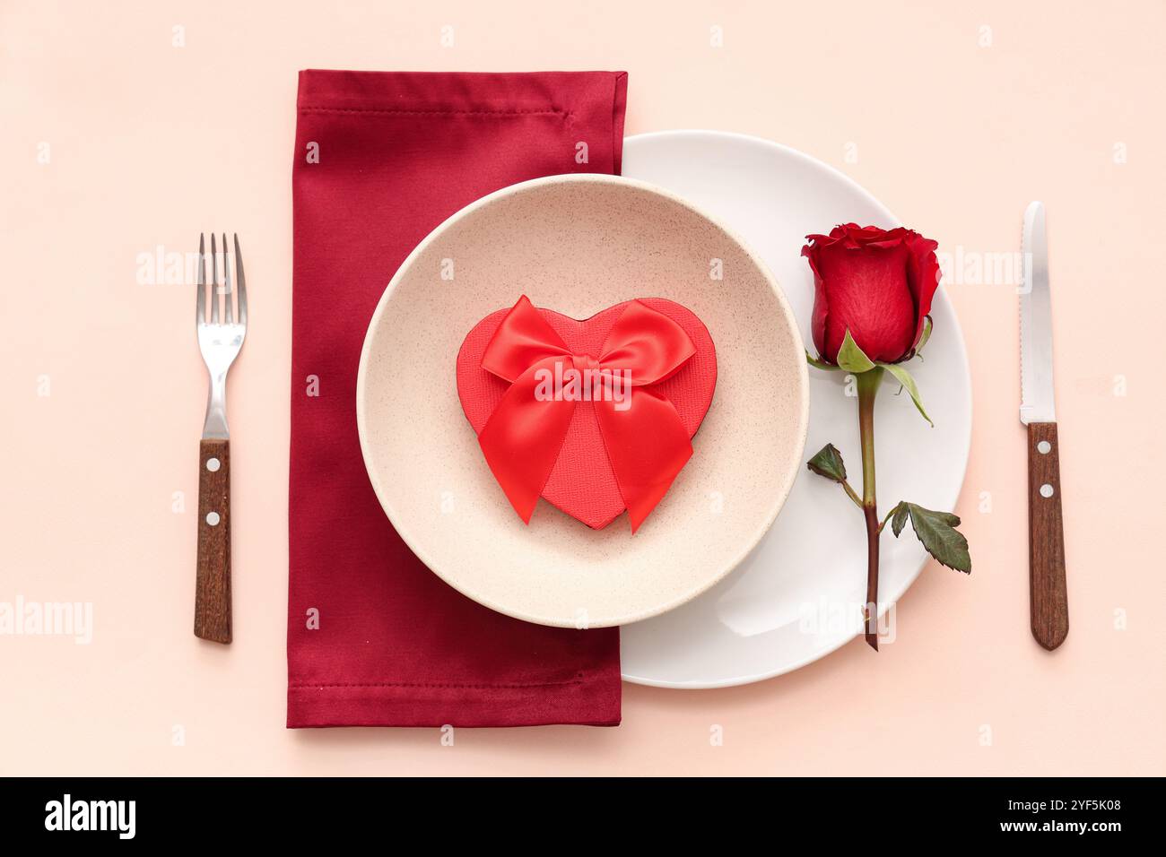 Beautiful table setting with red rose and gift box on beige background ...
