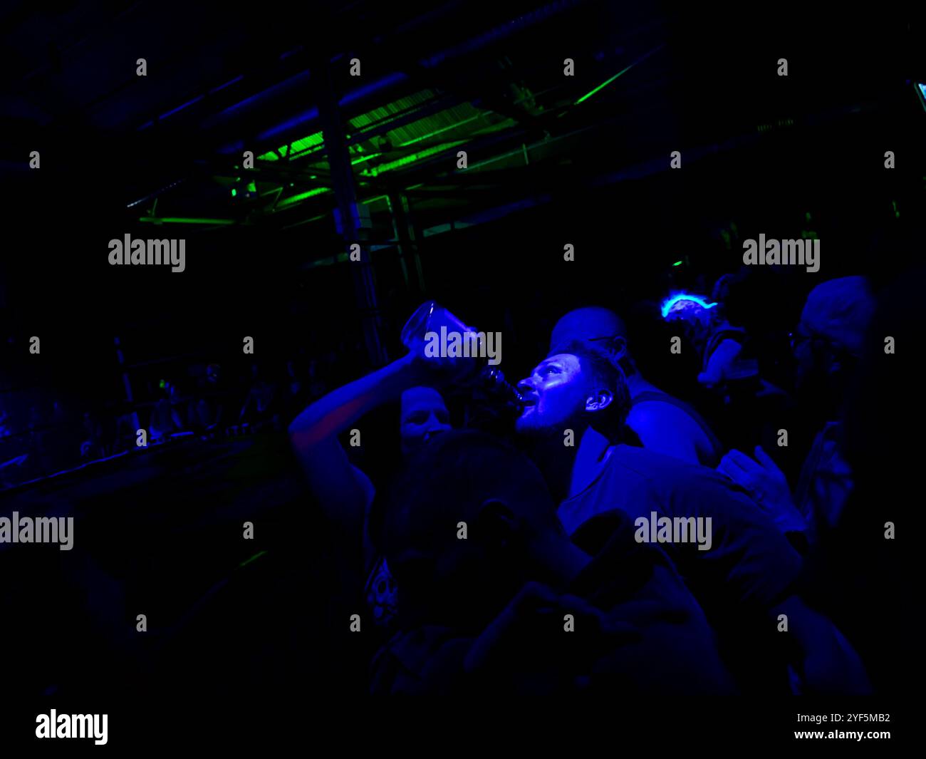 A man getting a shot out of a bottle ringside at the Rock n Roll Wrestling Bash in the Festsaal Kreuzberg, Berlin - Smartphone Captured Stock Image