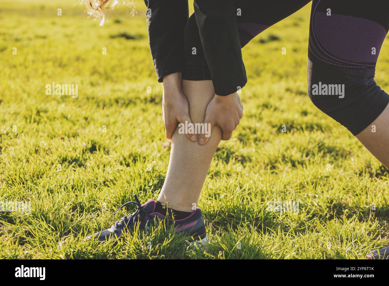 A view of a person holding the calf muscle in pain. Stock Photo