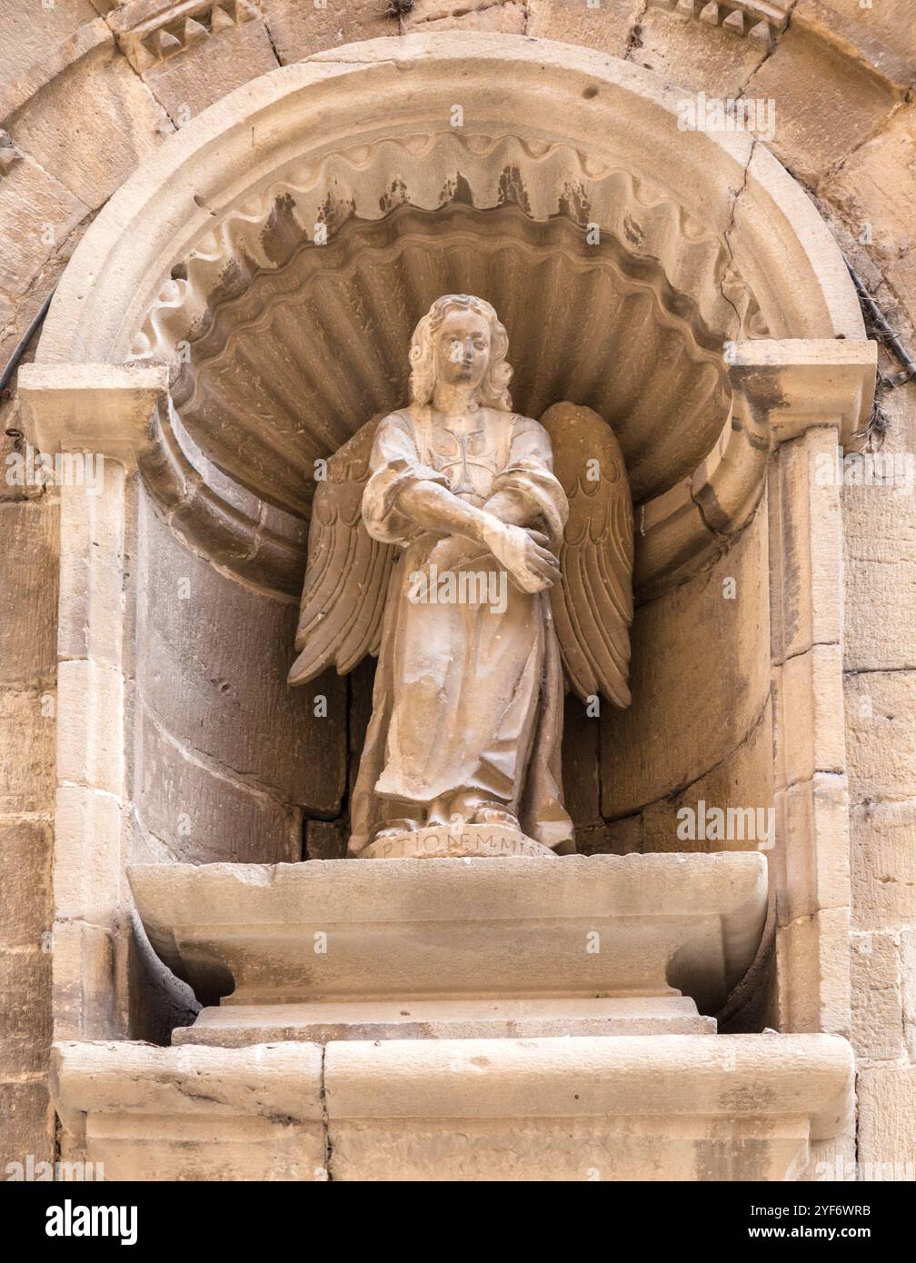 The beautifully carved angel stands serenely in its niche, showcasing intricate details against the stone backdrop. Stock Photo